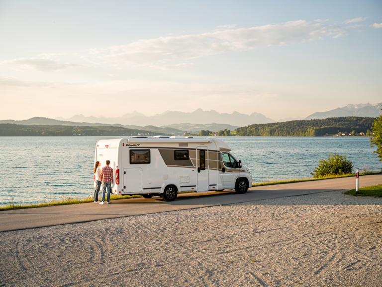 Wohnmobil am Bodensee auf ruhiger Straße mit Alpenpanorama im Hintergrund