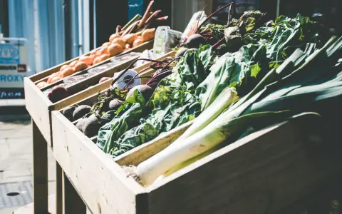 Symbolbild: An array of fresh vegetables at an outdoor market stall, showcasing green leafy produce.