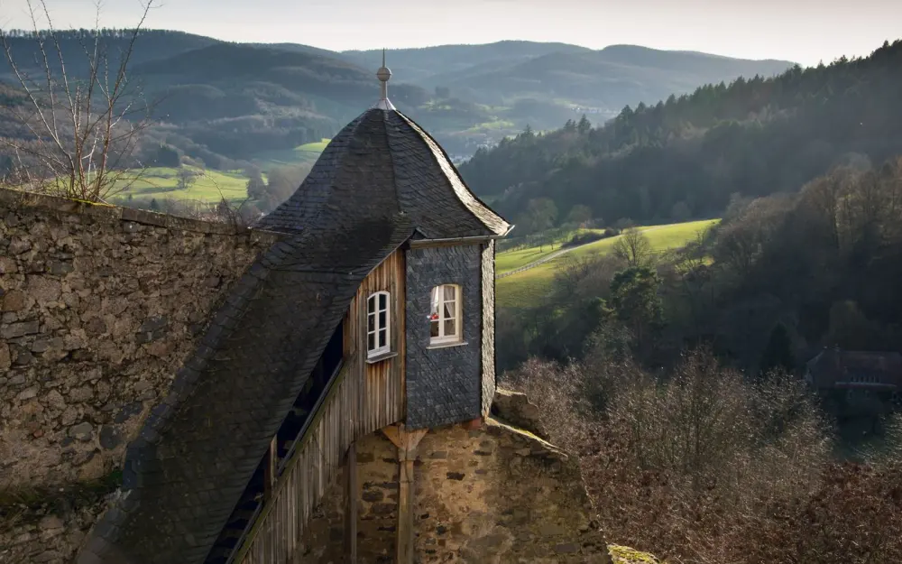Symbolbild: Picturesque view of a historic guardhouse and lush German countryside with rolling hills.