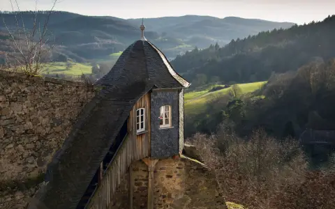 Symbolbild: Picturesque view of a historic guardhouse and lush German countryside with rolling hills.