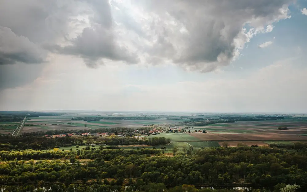 Symbolbild: Scenic aerial view of lush countryside with clouds and vibrant fields.