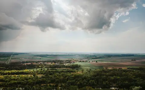 Symbolbild: Scenic aerial view of lush countryside with clouds and vibrant fields.