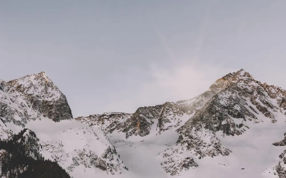 Symbolbild: Spectacular view of serene snow-capped mountain peaks bathed in soft sunrise light.