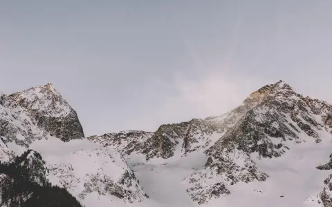 Symbolbild: Spectacular view of serene snow-capped mountain peaks bathed in soft sunrise light.