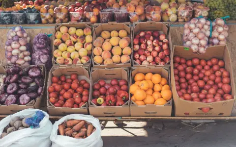 Symbolbild: Colorful fruits and vegetables arranged in boxes at an outdoor market stall.