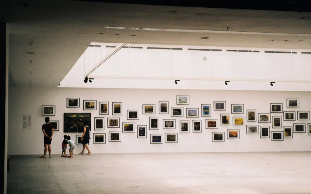 Symbolbild: A family exploring an art exhibition in a modern gallery with framed artworks displayed on the wall.