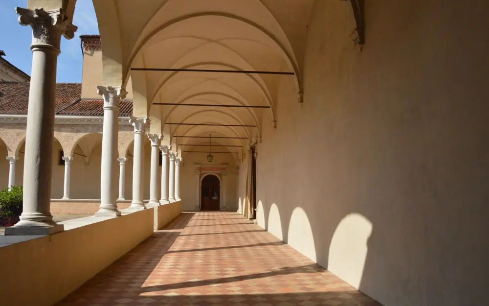 Symbolbild: A serene monastery walkway featuring arches and columns, creating a peaceful ambiance.