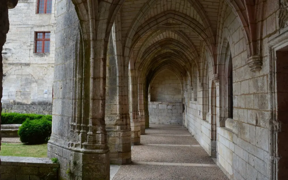 Symbolbild: A serene gothic cloister passage featuring arched stone columns and a tranquil atmosphere.