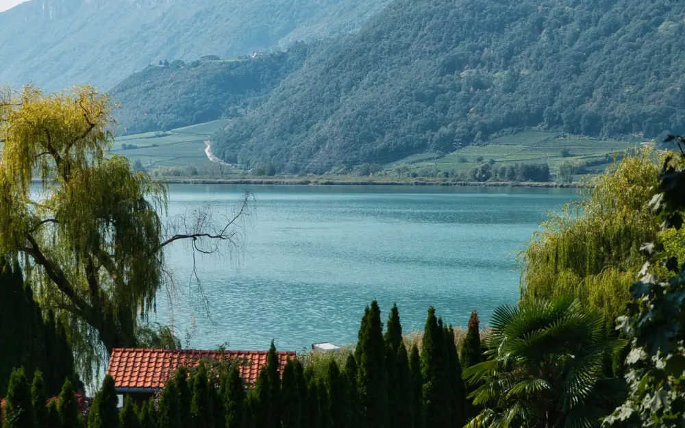 Symbolbild: Tranquil view of Kaltern Lake with lush greenery and mountain backdrop in Trentino-Südtirol, Italy.