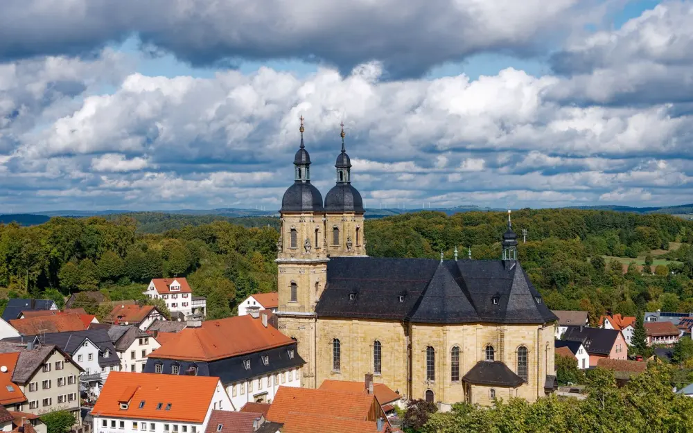 Symbolbild: Aerial view of the Gößweinstein Basilica and quaint town in Bavaria under dramatic clouds.