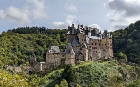 Symbolbild: Majestic Eltz Castle amidst lush forests in Wierschem, Germany, under a cloudy sky.