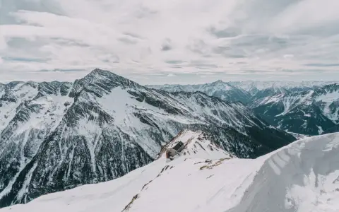 Symbolbild: A stark winter scene with snow-covered mountains and a secluded hut.