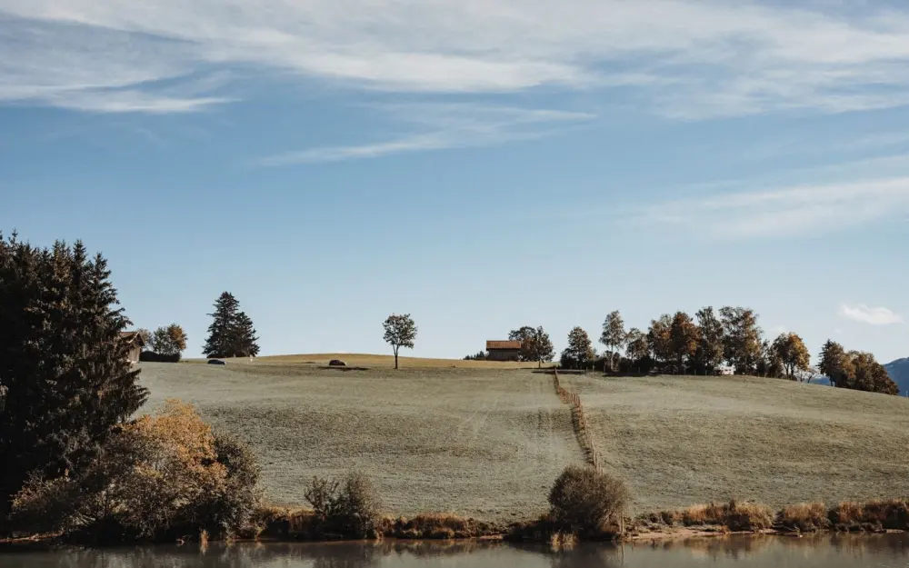 Symbolbild: Beautiful Bavarian countryside landscape featuring a serene farmhouse, trees, and peaceful fields.