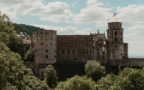 Symbolbild: Heidelberg Castle seen amidst lush summer greenery, showcasing iconic gothic architecture.