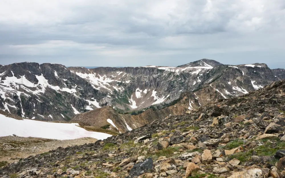Symbolbild: A stunning view of a snow-dusted mountain range under an overcast sky.