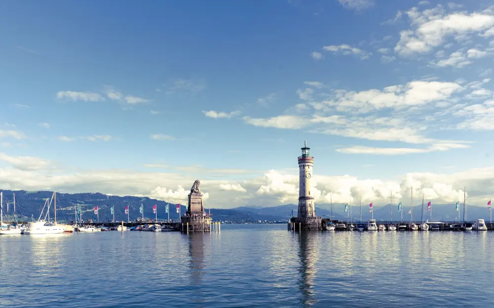 Stunning scene of Lindau Harbor featuring the iconic lighthouse and tranquil waters.