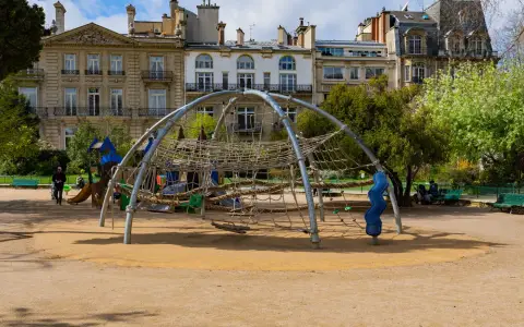 Symbolbild: A modern playground with climbing structures in a sunny urban park.