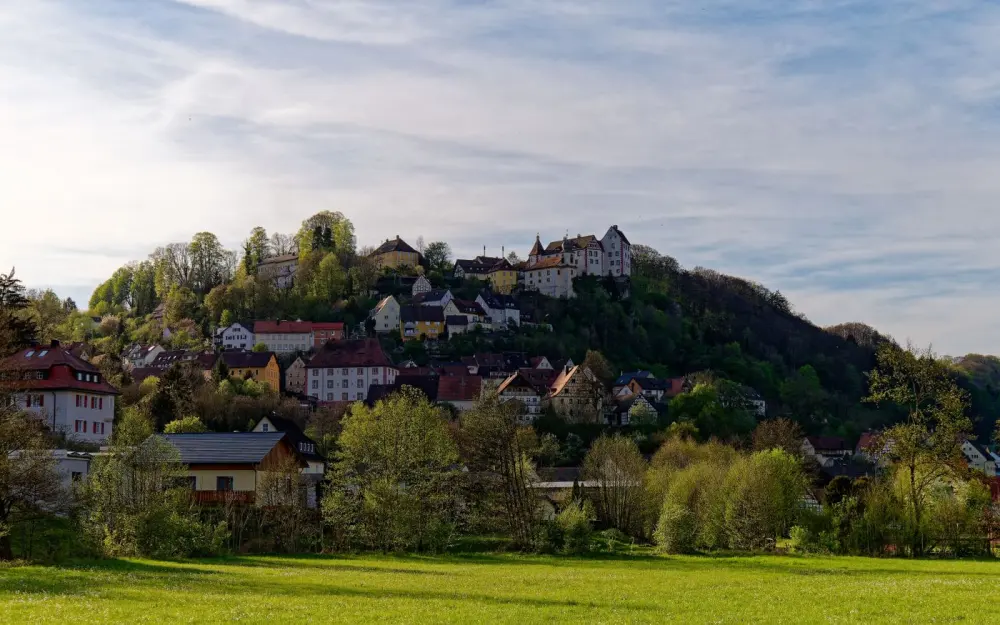 Symbolbild: Picturesque hillside village of Egloffstein in Bavaria, Germany, surrounded by lush greenery.