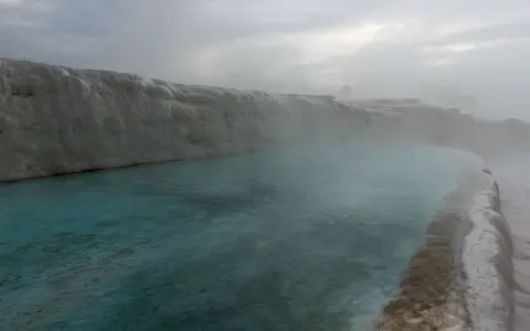 Symbolbild: Misty morning at Pamukkale's thermal springs, showcasing natural beauty and calm waters.