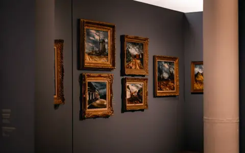 Symbolbild: Elegant art gallery with framed paintings on a dimly lit wall, showcasing artistic works.