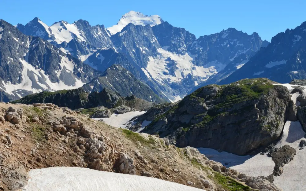 Symbolbild: Breathtaking view of a rocky mountain range with snow-capped peaks under a clear blue sky.