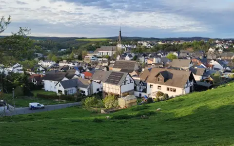 Symbolbild: Picturesque view of Villmar, Germany showcasing charming houses and church on a lush hillside.