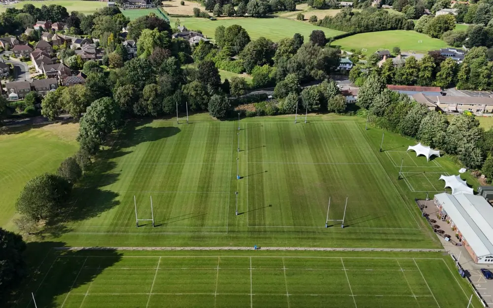 Symbolbild: Aerial view of rugby fields surrounded by trees and houses in North Yorkshire, England.
