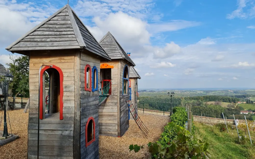 Symbolbild: Rustic wooden playground castle with a scenic rural view under a bright sky.