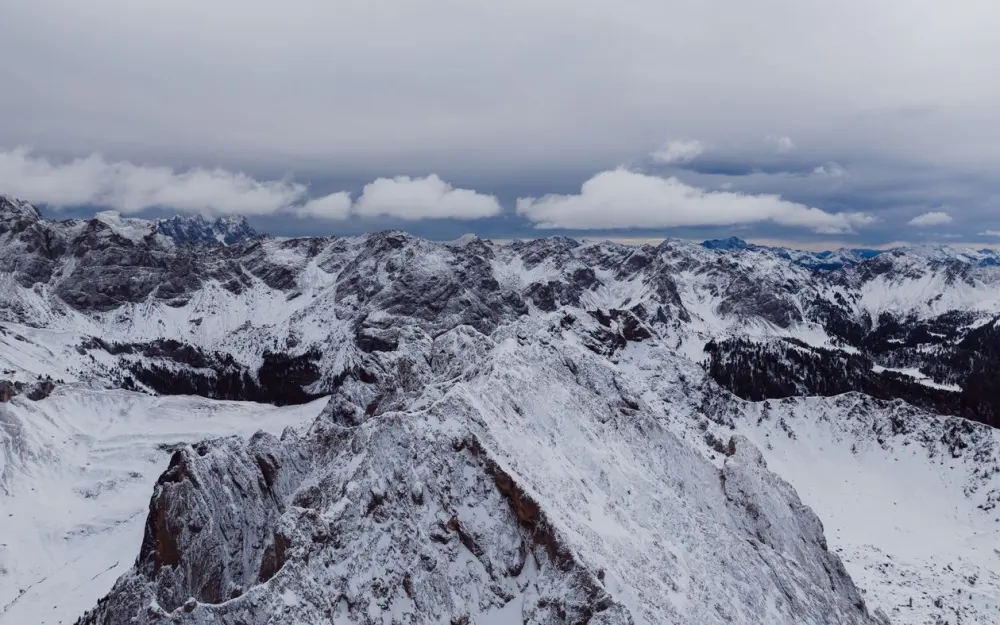 Symbolbild: Scenic winter aerial of the snow-covered Dolomites in Canazei, Italy, showcasing rugged peaks.