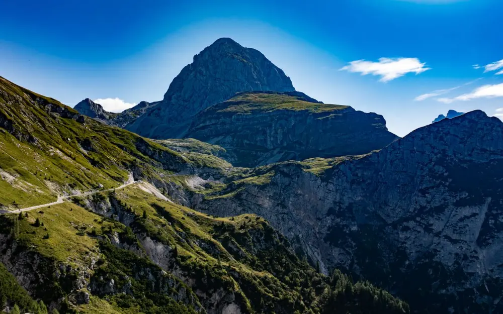Symbolbild: Breathtaking view of a mountain landscape with a winding path under clear blue skies.