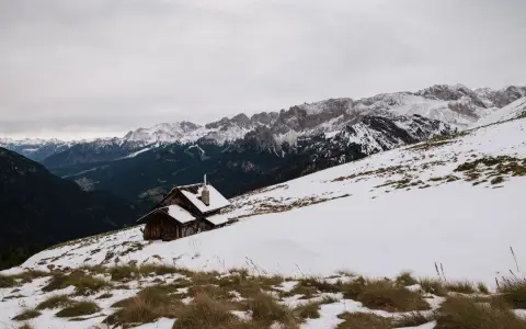 Symbolbild: Scenic view of a snowy mountain landscape with a wooden cabin in Canazei, Italy.