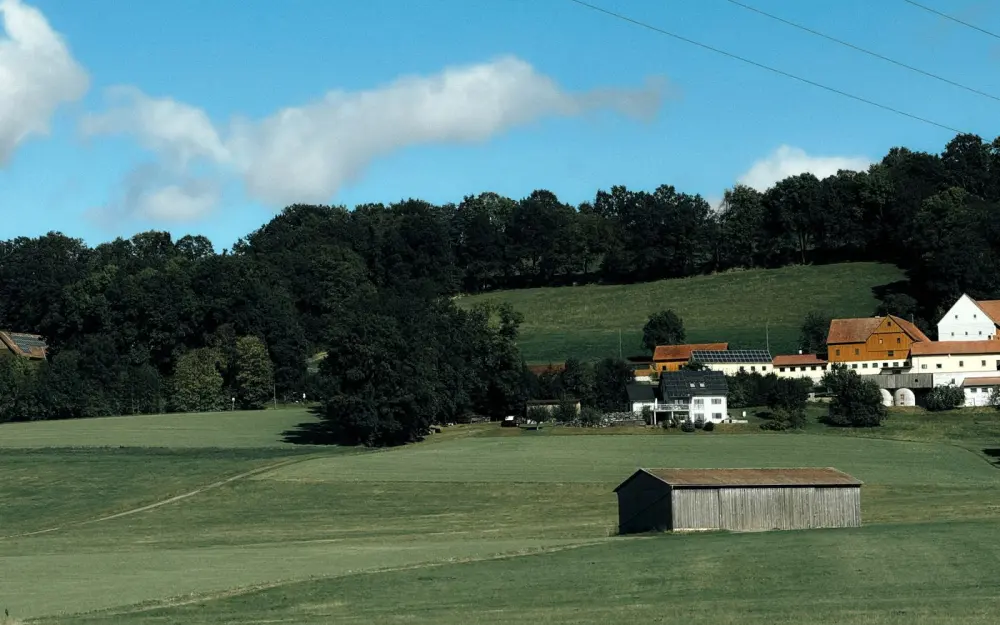Symbolbild: Scenic countryside view in Bad Berneck, Germany, with fields and farm buildings.
