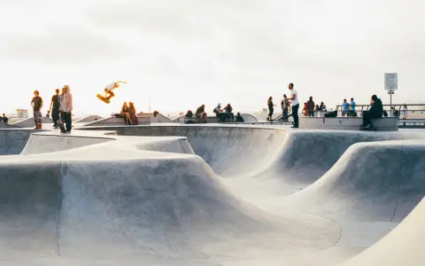 Symbolbild: A vibrant scene of skateboarders performing tricks at a lively outdoor skatepark.