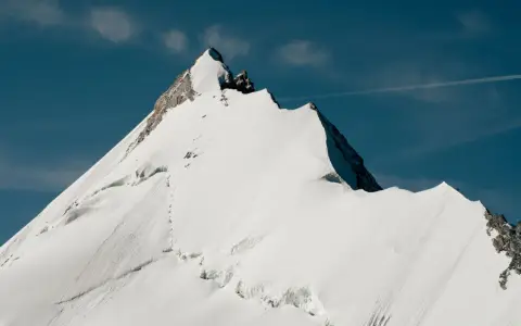 Symbolbild: Stunning snow-covered alpine mountain peak against a clear blue sky, showcasing natural beauty.