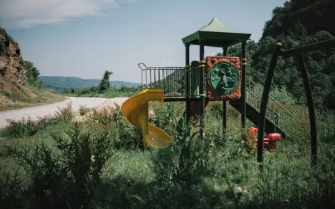 Symbolbild: An unused playground surrounded by nature in a rural countryside setting.