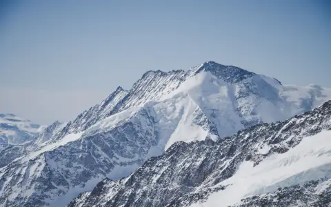Symbolbild: Stunning view of snow-covered Alps in Switzerland beneath a clear blue sky, capturing the essence of winter beauty.