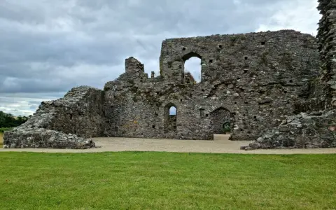 Symbolbild: Explore the architectural charm of ancient stone ruins with large archways beneath a cloudy sky.