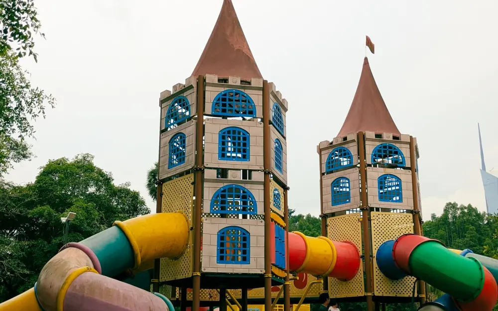 Symbolbild: Two playful castle-like structures with vibrant slides in a park setting, perfect for family fun.