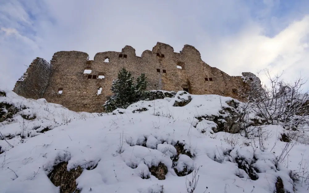 Symbolbild: Majestic castle ruins covered in snow under a winter sky.
