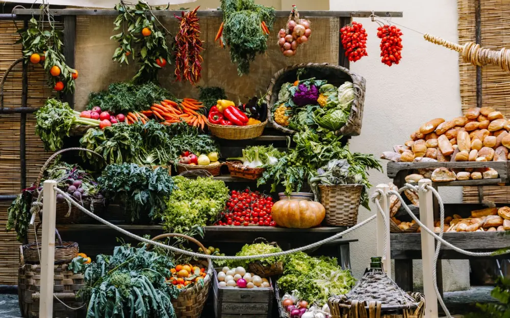 Symbolbild: Vibrant array of fresh produce and bread at a farmer's market stand, showcasing seasonal vegetables and baked goods.