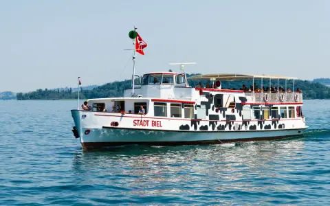 Symbolbild: Stadt Biel ferry cruising on Lake Biel under a clear sky with passengers on board.