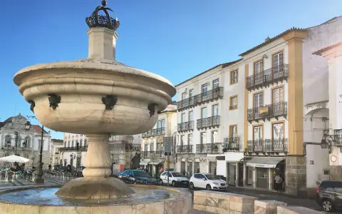 Symbolbild: Majestic stone fountain at Praça do Giraldo in Évora, Portugal, showcasing classic architecture.