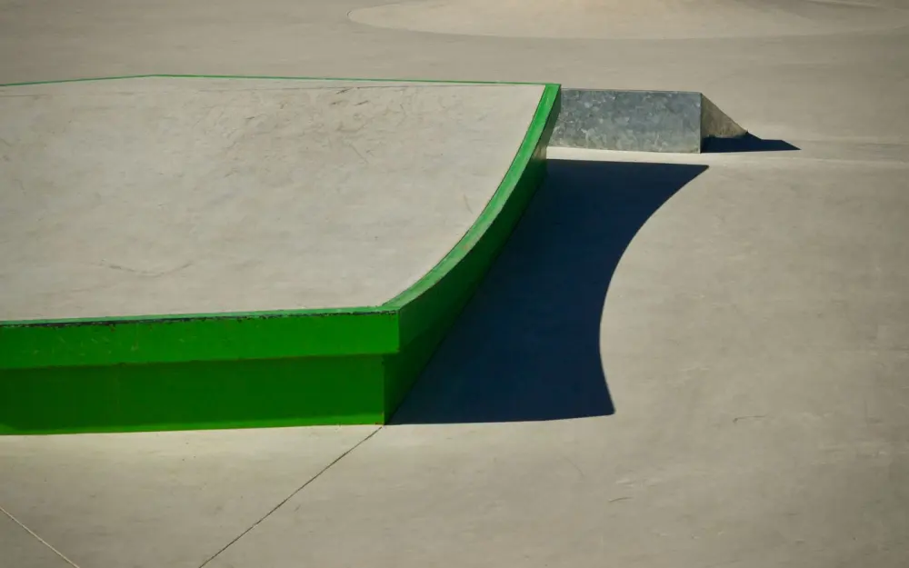 Symbolbild: A modern skatepark with a vibrant green curved ramp under bright sunlight.