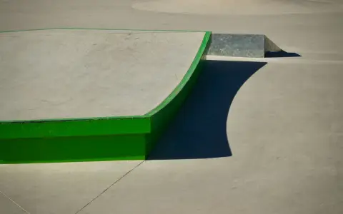 Symbolbild: A modern skatepark with a vibrant green curved ramp under bright sunlight.
