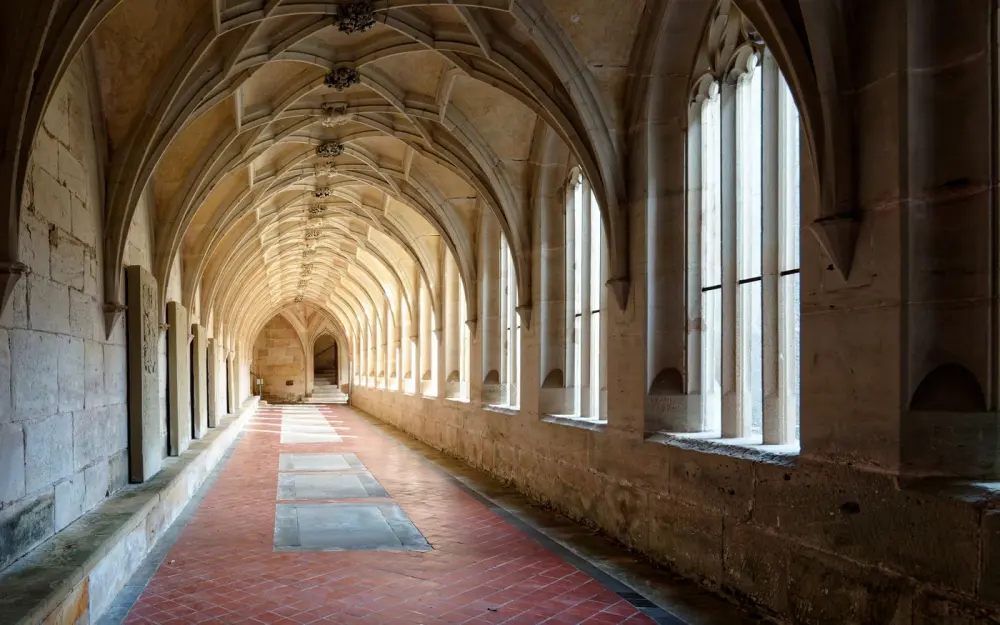 Symbolbild: A beautifully preserved Gothic cloister corridor with vaulted ceilings and stone arches.