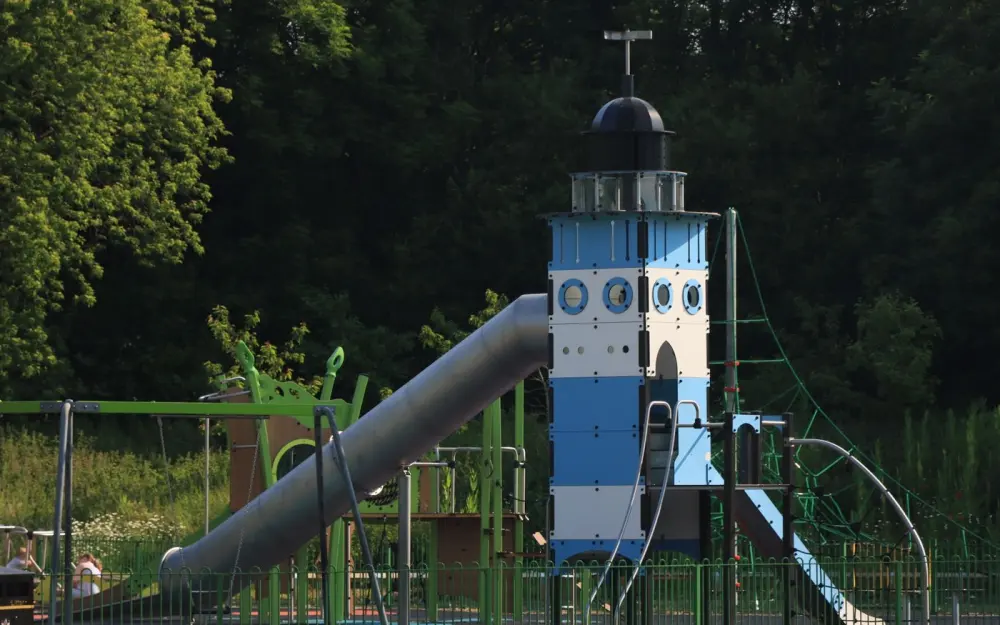 Symbolbild: A lighthouse-themed playground slide amidst trees in a park setting.