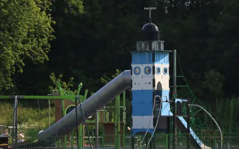 Symbolbild: A lighthouse-themed playground slide amidst trees in a park setting.
