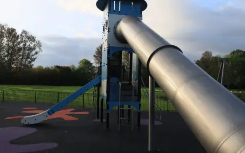 Symbolbild: A modern outdoor playground slide set in a green park in England.