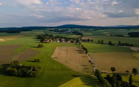 Symbolbild: Aerial shot of a picturesque rural landscape in Rehau, Germany, showcasing lush fields and a small village.