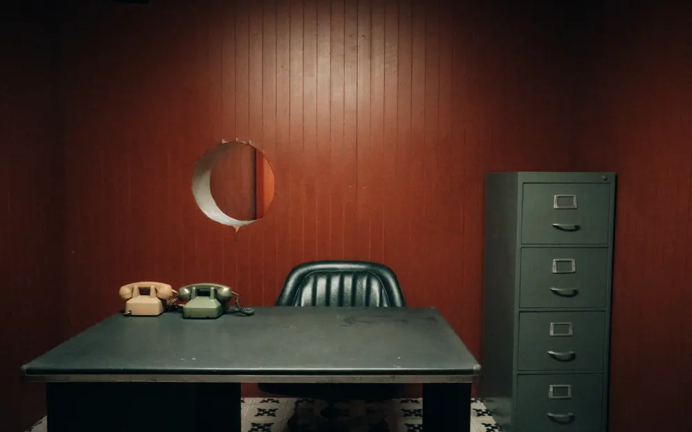 Symbolbild: Retro-styled office featuring vintage telephones, filing cabinet, and dark wood walls.